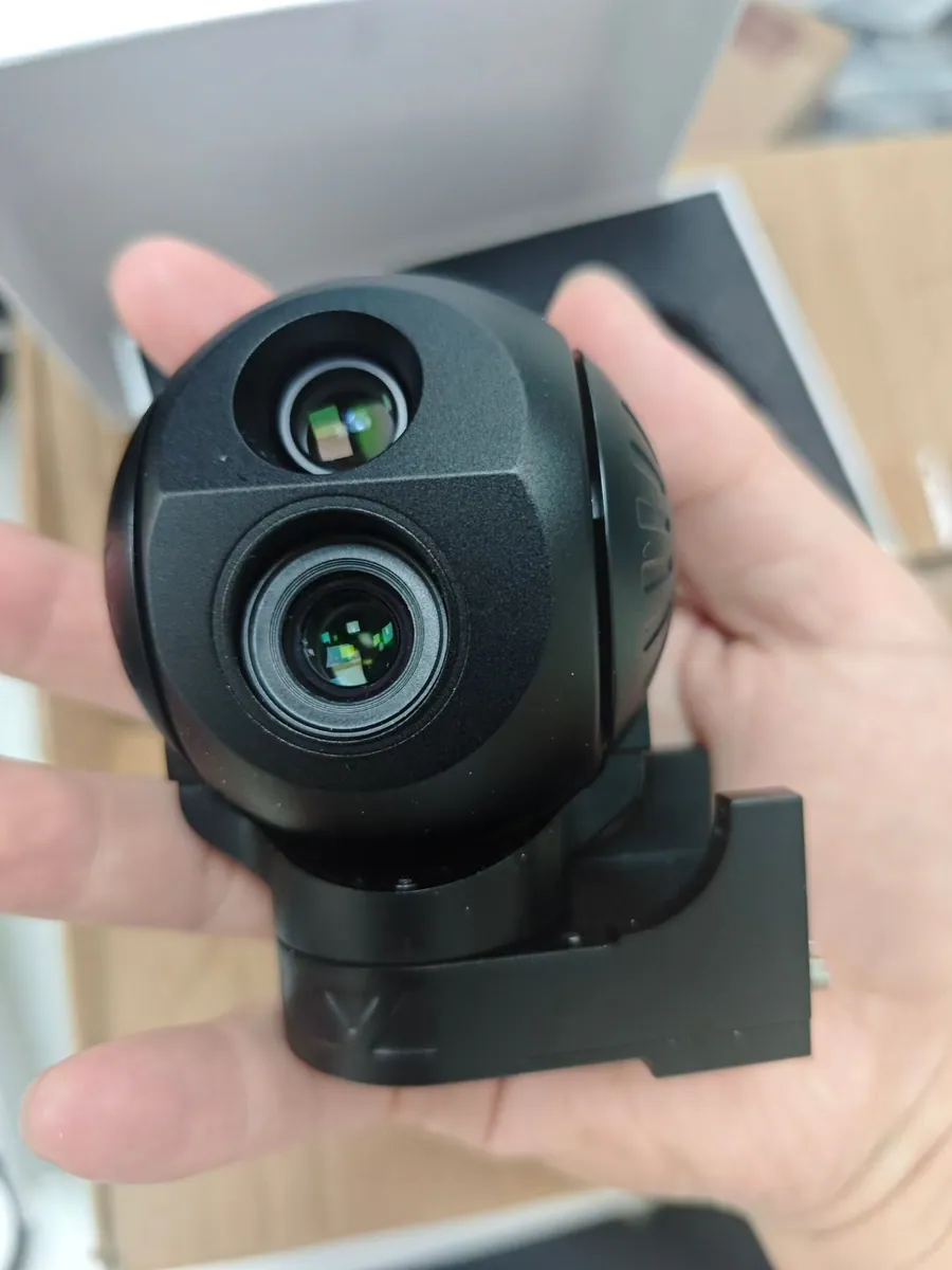 Compact two-axis gimbal camera payload held in the hand, showing the pitch and yaw bracket