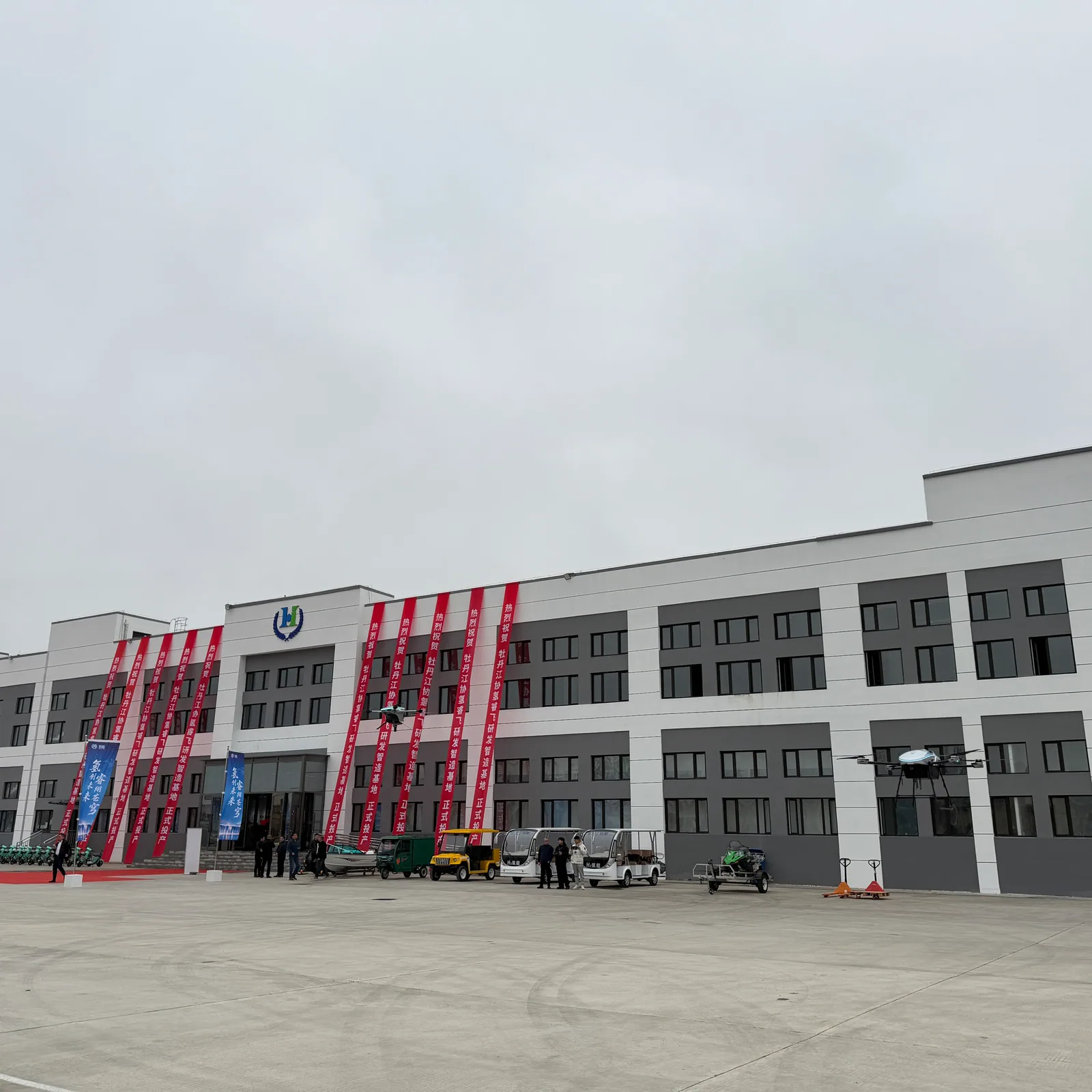 Celebration banners on the HITS Mudanjiang plant exterior with UAVs displayed in the forecourt