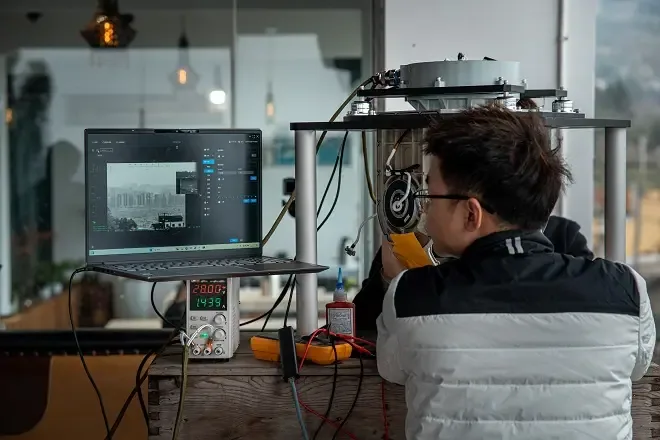 Engineer testing a HITS gimbal camera on a bench with a laptop running control software