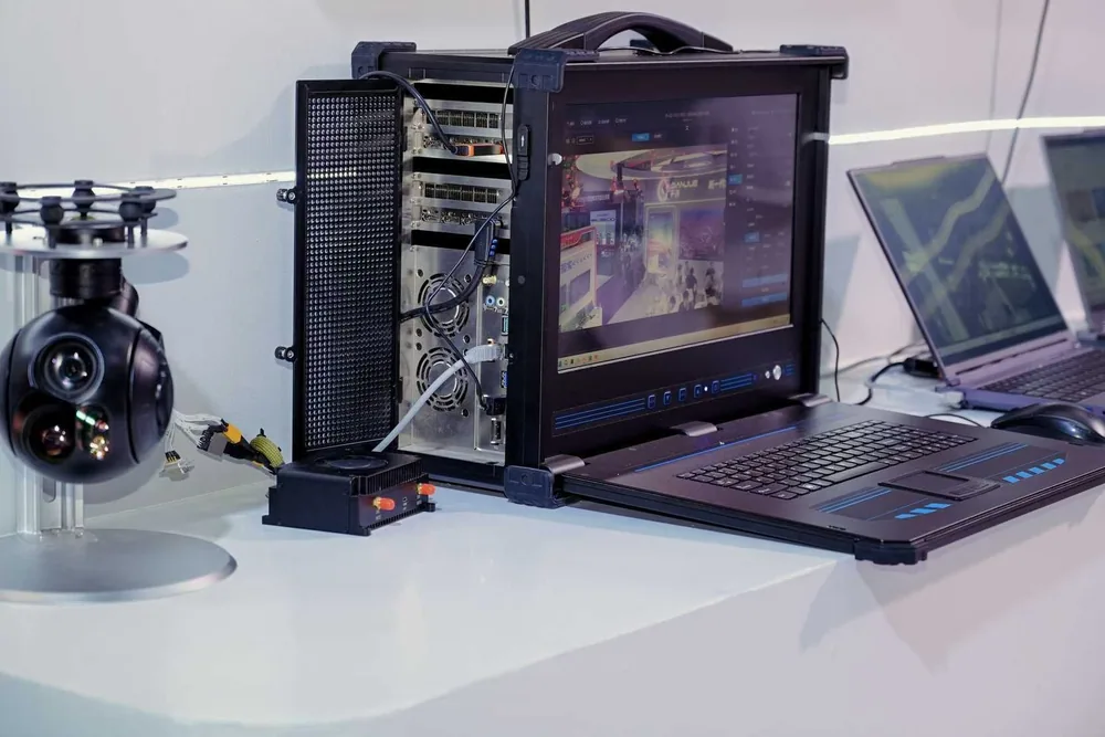 A HITS gimbal camera payload set up on a bench with a ground control station and operator displays